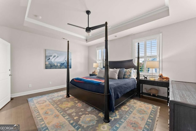 bedroom featuring a raised ceiling, ceiling fan, and dark hardwood / wood-style floors