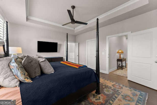 bedroom with dark hardwood / wood-style flooring, a tray ceiling, ceiling fan, and ornamental molding