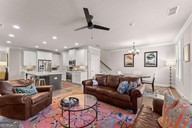 living room featuring ceiling fan with notable chandelier and ornamental molding