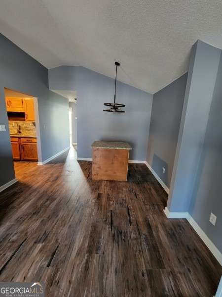 unfurnished dining area with lofted ceiling, sink, dark hardwood / wood-style floors, ceiling fan, and a textured ceiling