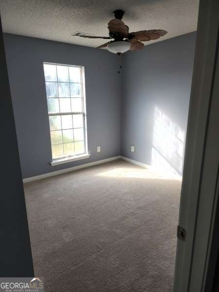 carpeted empty room with a textured ceiling and ceiling fan