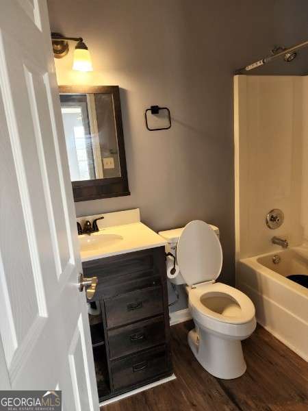 full bathroom with washtub / shower combination, wood-type flooring, vanity, and toilet