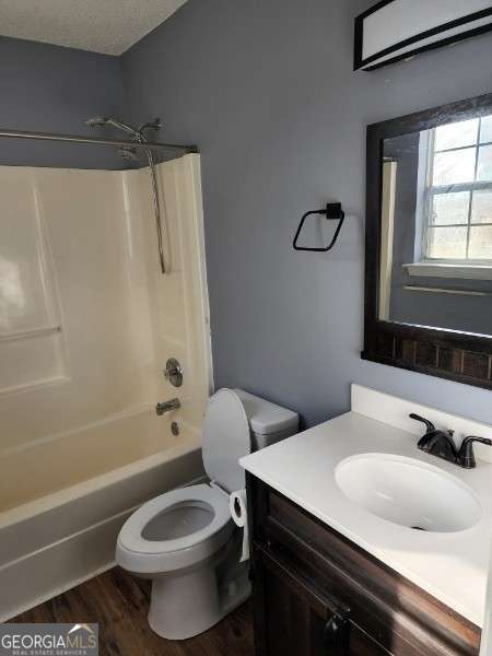 full bathroom with vanity, toilet, a textured ceiling, shower / bath combination, and wood-type flooring