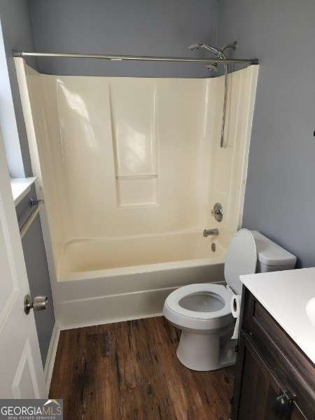 full bathroom with vanity, toilet, wood-type flooring, and shower / washtub combination