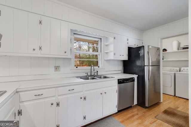 kitchen featuring washer and clothes dryer, sink, light hardwood / wood-style floors, white cabinetry, and stainless steel appliances