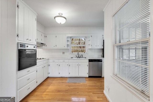 kitchen with black oven, light wood-type flooring, sink, dishwasher, and white cabinetry