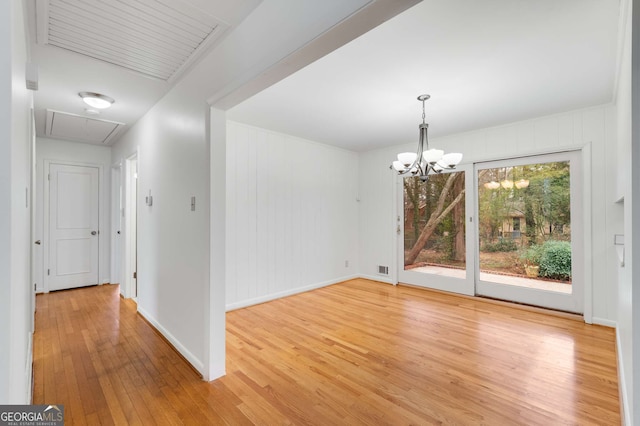 unfurnished dining area featuring a notable chandelier and light hardwood / wood-style floors