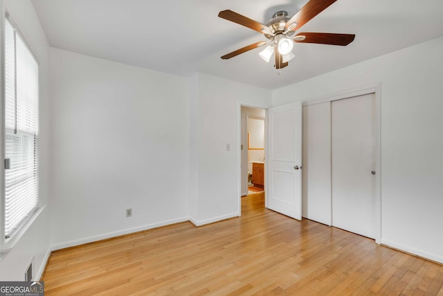 unfurnished bedroom with multiple windows, light wood-type flooring, a closet, and ceiling fan