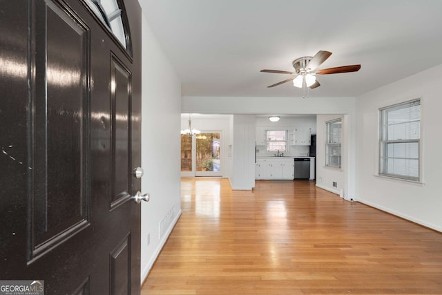 interior space featuring ceiling fan with notable chandelier, light wood-type flooring, and sink