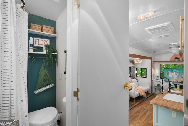 bathroom featuring vanity, toilet, wood-type flooring, and vaulted ceiling