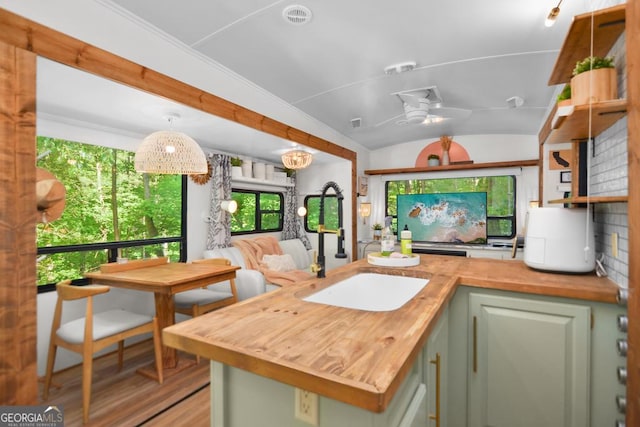 kitchen featuring wood counters, lofted ceiling, green cabinets, ceiling fan, and light hardwood / wood-style floors