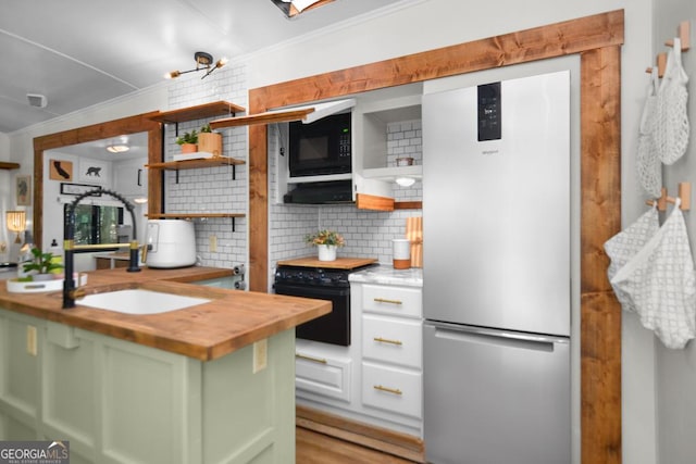 kitchen with sink, black appliances, green cabinetry, white cabinets, and butcher block counters