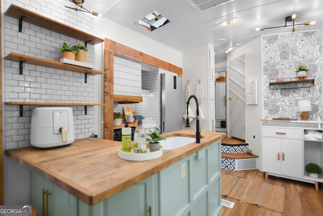 kitchen with wood counters, light hardwood / wood-style flooring, green cabinetry, and sink