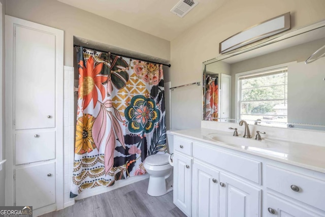 bathroom with wood-type flooring, vanity, toilet, and curtained shower