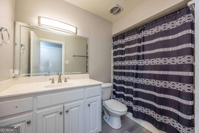 bathroom featuring walk in shower, vanity, wood-type flooring, and toilet