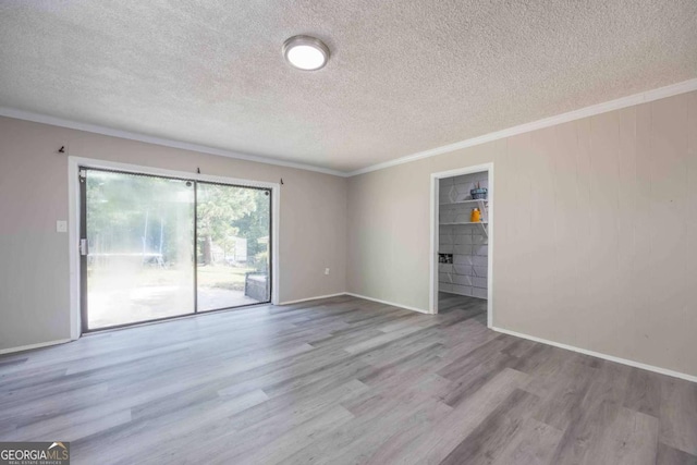 unfurnished room with a textured ceiling, light wood-type flooring, and ornamental molding