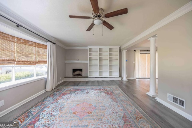 unfurnished living room featuring dark wood-type flooring, ceiling fan, crown molding, and decorative columns