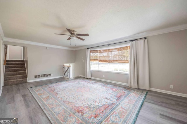 spare room featuring wood-type flooring, a textured ceiling, ceiling fan, and ornamental molding