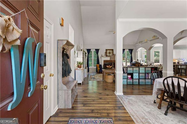 entrance foyer with lofted ceiling, crown molding, and dark wood-type flooring