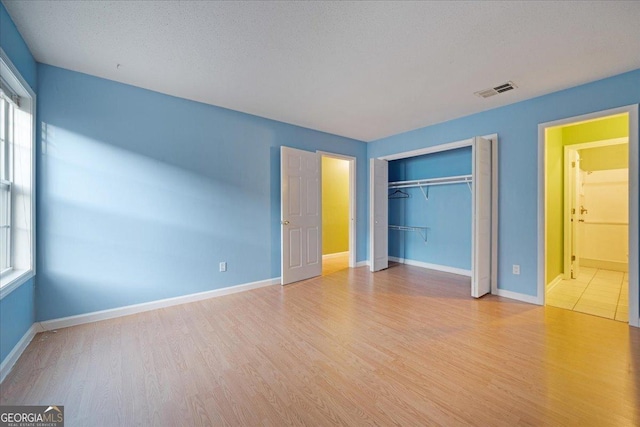 unfurnished bedroom featuring a textured ceiling, light hardwood / wood-style flooring, and a closet