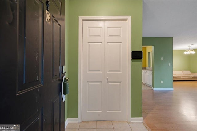entrance foyer with baseboards, an inviting chandelier, and light tile patterned floors