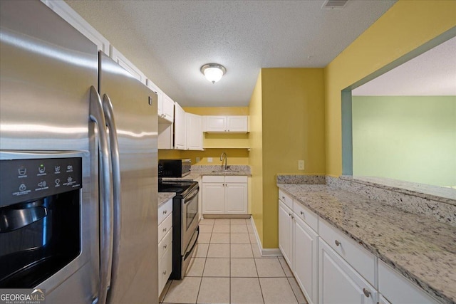 kitchen featuring a sink, stainless steel appliances, white cabinets, light stone counters, and light tile patterned flooring