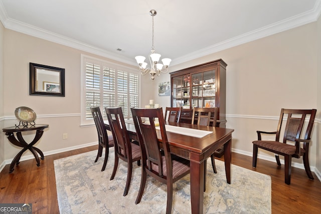 dining area featuring crown molding, dark hardwood / wood-style floors, and a notable chandelier