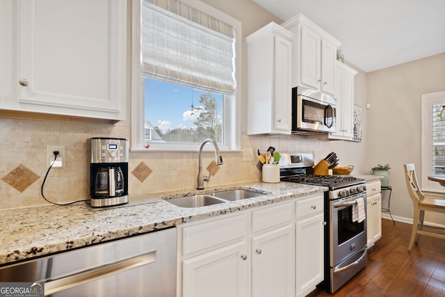 kitchen featuring sink, dark hardwood / wood-style floors, appliances with stainless steel finishes, light stone counters, and white cabinetry