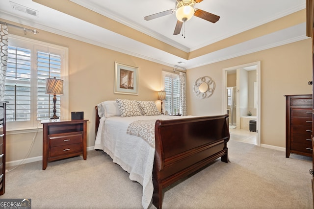 bedroom featuring ensuite bath, ornamental molding, light colored carpet, a raised ceiling, and ceiling fan