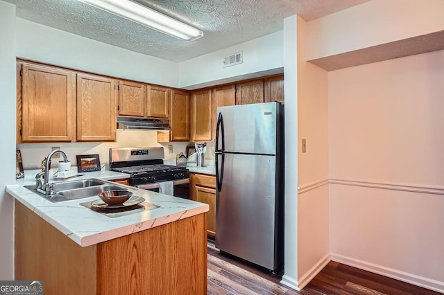 kitchen featuring sink, stainless steel appliances, dark hardwood / wood-style floors, kitchen peninsula, and a textured ceiling