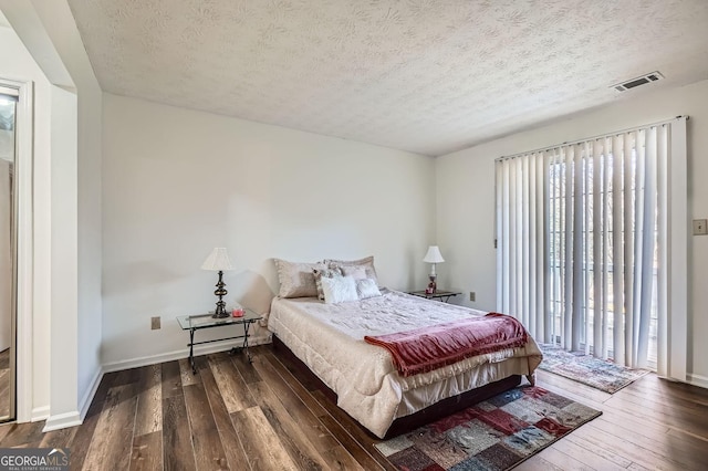 bedroom featuring dark hardwood / wood-style flooring and a textured ceiling