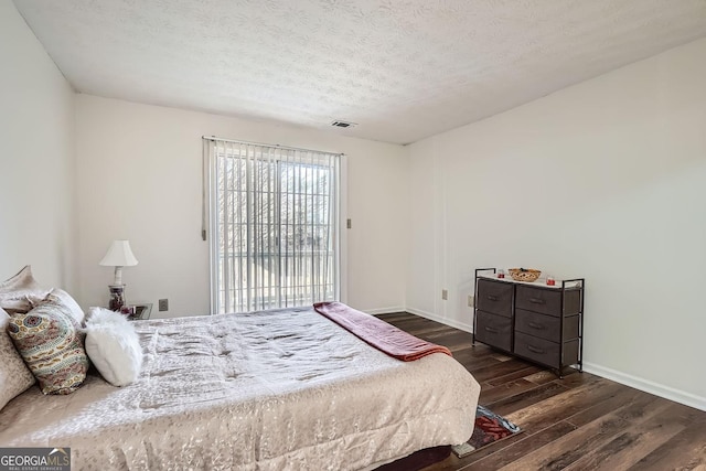 bedroom with a textured ceiling, dark hardwood / wood-style floors, and access to outside