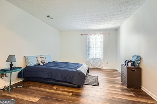 bedroom with dark wood-type flooring and a textured ceiling