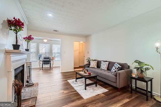 living room with dark hardwood / wood-style floors, ceiling fan, ornamental molding, and a textured ceiling