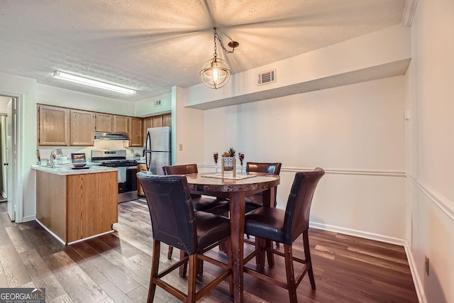 dining area featuring sink, dark hardwood / wood-style floors, and a textured ceiling