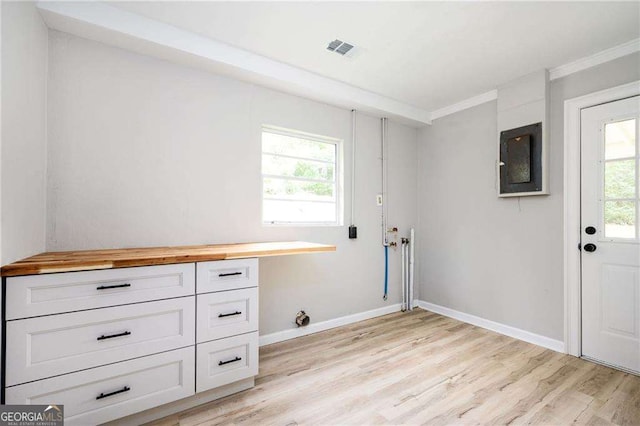 laundry area featuring light wood-type flooring and crown molding