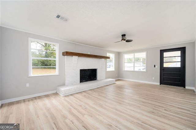 unfurnished living room featuring crown molding, a fireplace, ceiling fan, and light hardwood / wood-style floors