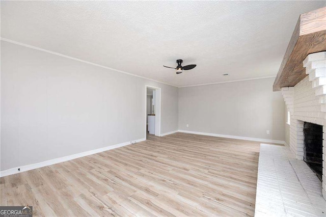 unfurnished living room featuring ornamental molding, a textured ceiling, ceiling fan, light hardwood / wood-style flooring, and a fireplace