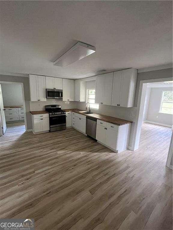 kitchen featuring white cabinets, stainless steel appliances, plenty of natural light, and dark wood-type flooring