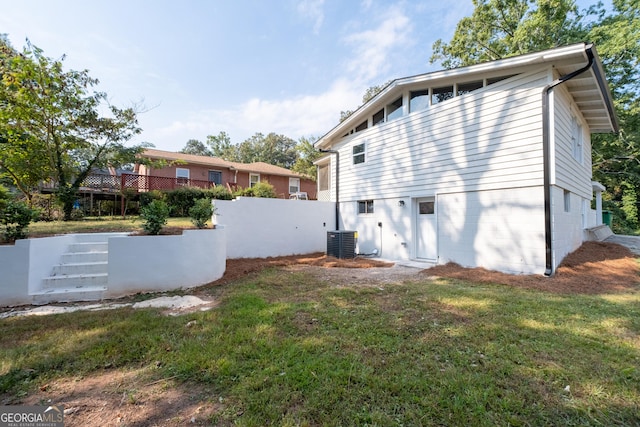 rear view of house featuring a lawn and central air condition unit