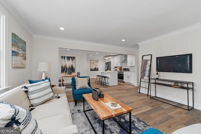 living room with a chandelier, crown molding, and light hardwood / wood-style flooring