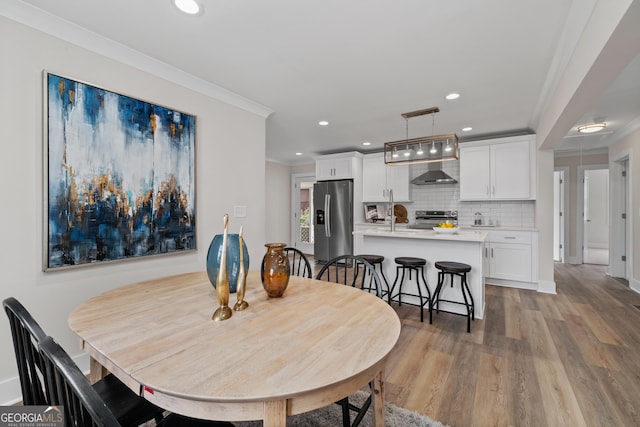 dining space featuring crown molding, hardwood / wood-style floors, and sink