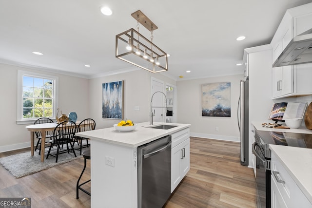 kitchen with pendant lighting, white cabinets, a center island with sink, sink, and appliances with stainless steel finishes