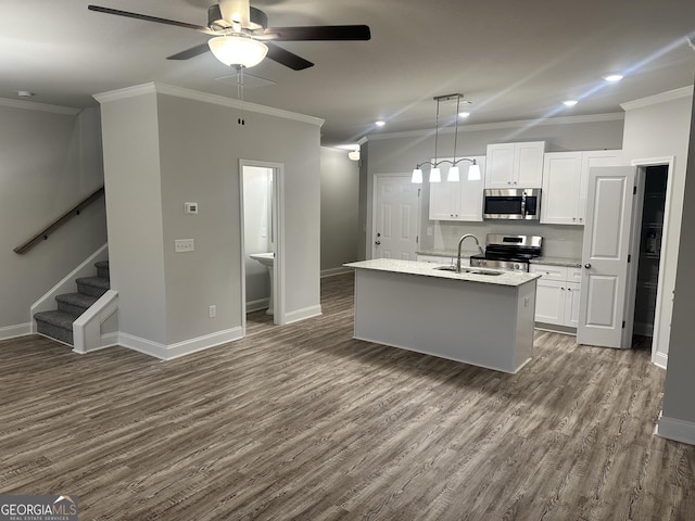 kitchen featuring white cabinets, stainless steel appliances, crown molding, and an island with sink