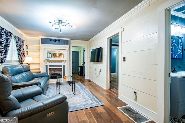 living room featuring sink, hardwood / wood-style floors, an inviting chandelier, and ornamental molding