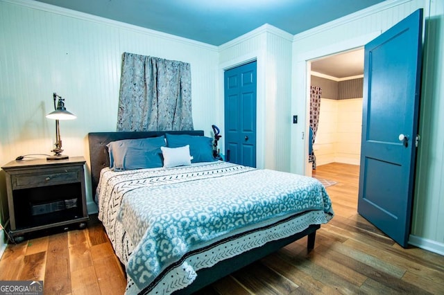 bedroom with wood-type flooring, ornamental molding, and a closet