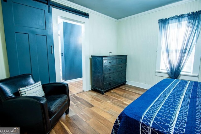 bedroom featuring hardwood / wood-style floors, a barn door, and ornamental molding