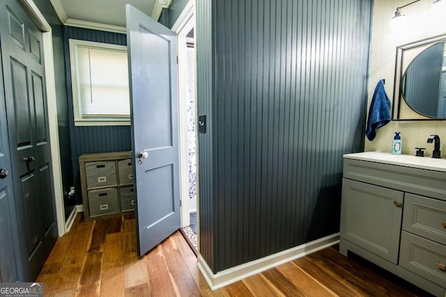 bathroom with crown molding, vanity, and wood-type flooring