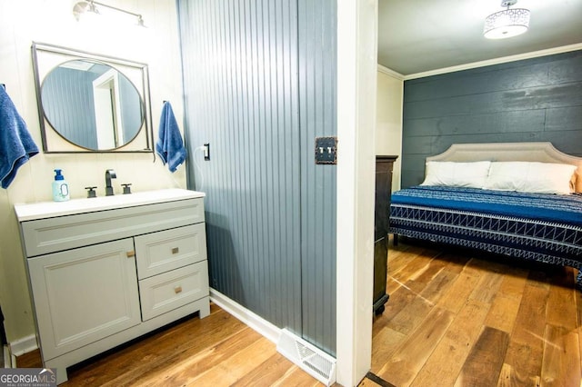 bathroom with hardwood / wood-style flooring, vanity, wood walls, and crown molding