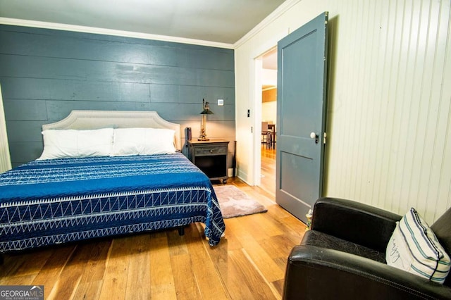 bedroom featuring wooden walls, hardwood / wood-style flooring, and crown molding